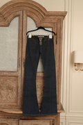 Front view of dark wash Electric Barbarella  jeans hanging on a wooden cabinet, featuring a black leather-trimmed waistband and a white lace-up leather closure at the fly.