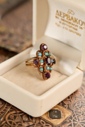 Close-up of a vintage 18k yellow gold statement ring. Displays a rich cluster of faceted purple amethysts and smooth, round turquoise cabochons set in ornate gold.
