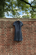 Ralph Lauren short-sleeve button-front dress hanging from a wooden hanger on a brick wall. 