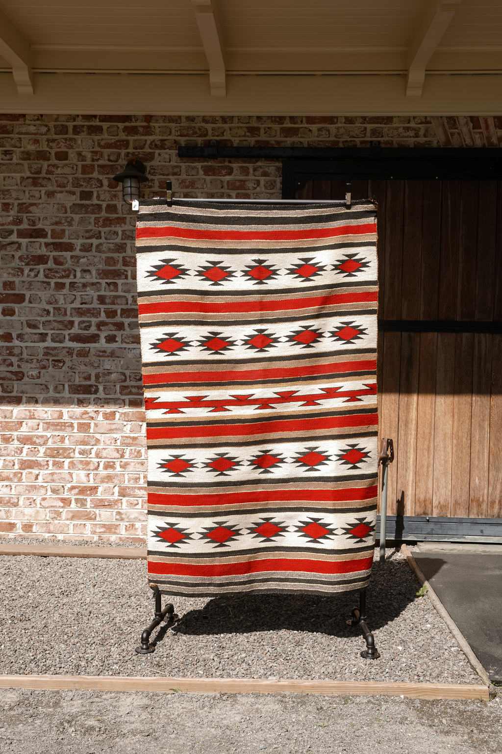 Handwoven Navajo textile with horizontal bands and red diamond motifs